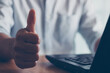 © THAWEERAT - Close up of businessman showing raised thumbs at the camera as a gesture of recommendation or good choice. Professional support and service team demonstrates satisfaction and gives a positive response