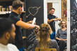 © PoppyPix - Hair salon visit. Busy professional hairdresser during hair blow-dry process. Satisfied client seen in mirror reflection. High quality photo