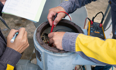 A multimeter is being used by an electrician to check the resistance and dielectric strength of an electric motor that is installed in a manufacturing facility. Inspect electric motors for anomalies