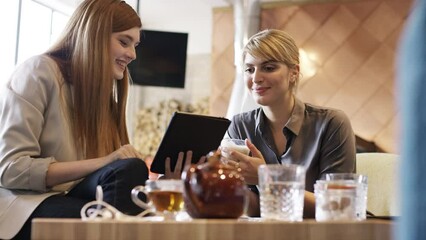 Poster - Business women, cafe and planning on tablet, discussion and strategy, ideas and website innovation in restaurant. Two young female designers working on digital marketing app technology in coffee shop