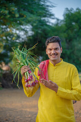 Wall Mural - Young indian farmer holding onion crop in hand at agriculture field