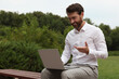© New Africa - Handsome businessman with laptop on bench in park