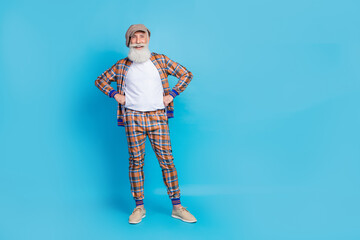 Wall Mural - Full length photo of positive funky man dressed trendy plaid clothes hand waist stand empty space isolated on blue color background