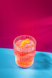 Negroni cocktail on pink and blue background. Italian IBA drink with gin, vermouth and orange. Fresh stir with ice. Classic alcoholic beverage at the sunny bar in harsh light. Colorful, creative