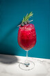 Cocktail on blue, marble background. Modern, stylish drink at the bar, night club or restaurant. Blueberry and rosemary garnish. Refreshing alcoholic beverage with gin, fruit juice and ice in glass