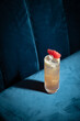 Cocktail on blue background. Modern, stylish drink placed on velvet couch at the bar, night club or restaurant. Refreshing alcoholic beverage with grapefruit and gin in highball glass. Copy space