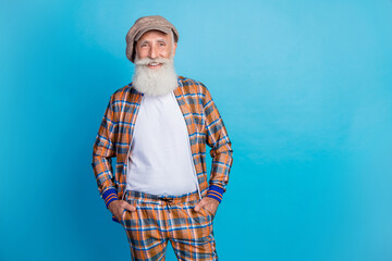 Poster - Photo of charming cheerful retired man dressed plaid suit hands arms pockets empty space isolated blue color background