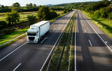 White truck driving on the highway winding through forested landscape in autumn colors at sunset