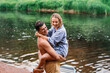 © Iona - Happy couple on vacation outdoors embracing  on the beach at river sailing having fun on nature. Cheerful caucasian young man lifts up his wife. Rest, leisure activities and travel.