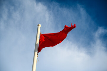 Red flag on beach as warning for high hazard  or strong currents. 