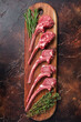 Raw Lamb chop steak on butcher board with rosemary and thyme. Dark background. Top view