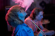 © DragonImages - Side view of young Black woman exhaling hookah smoke