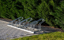 Image Of Empty Bicycle Parking Rack In Front Of A Row Of Hedges.