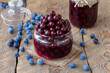 Homemade marinated Blackthorn or Sloe served in glass jar with fresh fruits on background.  Selective focus, horizontal, wooden table.
