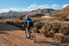 Woman Cyclist Riding A Gravel Bicycle On The Road In Hills With Mountain View, Alicante Region In Spain 
