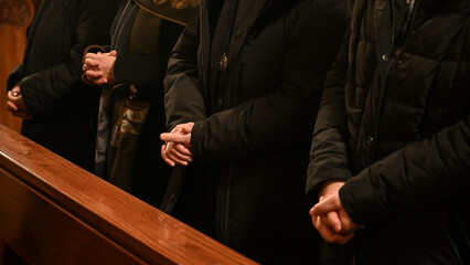 Wall Mural - Catholic nun praying with hands folded and fingers crossed during Christmas Midnight Mass in church.  Praying hands of Christian woman praying in Cathedral. 