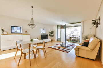 a living room with wood flooring and white furniture, including a dining table and two chairs in front of the window