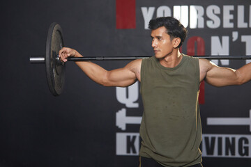 Wall Mural - young athletic man exercising with barbell in the gym