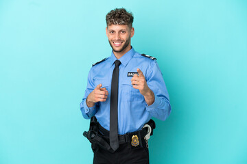 Wall Mural - Young police blonde man isolated white on blue background pointing to the front and smiling