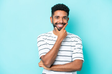 Wall Mural - Young Brazilian man isolated on blue background happy and smiling