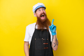 Wall Mural - Fishmonger wearing an apron isolated on yellow background pointing up and surprised