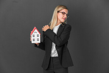 Wall Mural - Blonde Uruguayan girl holding a house toy isolated on black background suffering from pain in shoulder for having made an effort