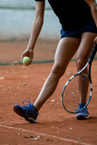 Fototapeta Sport - close-up shot of legs of woman tennis player with tennis racket and ball in her hand.