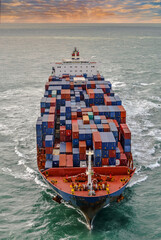 nice aerial view of a giant container ship sailing at dawn in the english channel