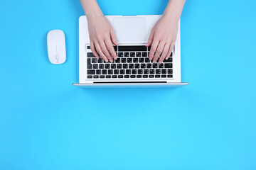 Poster - Female hands typing on laptop keyboard with mouse on blue background