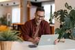 © Dorde - Content young businessman typing on a laptop, writing an e-mail, working and smiling. Home office concept.