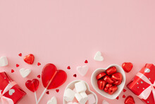 Valentine's Day concept. Flat lay photo of gift boxes, heart shaped lollipops, confectionery chocolate candies and marshmallow on pastel pink background with copy space. Sweet Valentines card idea.