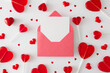 Valentine's Day concept. Flat lay photo of red heart shaped lollipops, heart sprinkles and envelope with letter in the middle on white background. Sweet Valentines card idea.