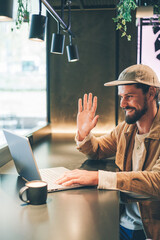 caucasian young man videocalling with laptop in a cafe