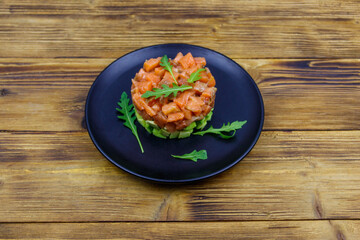 Wall Mural - Salmon tartare with avocado and arugula on wooden table