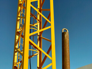 metal structure of a metallic construction site jib crane and the blue sky in the background