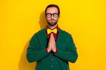 Wall Mural - Photo of young funny closed eyes gentleman wear stylish bowtie hands together pray for ukrainian peace stop war isolated on yellow color background