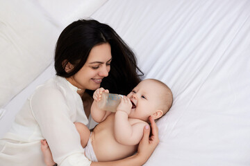 happy mother feeding her newborn baby on the bed