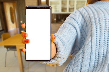 Poster - Phone white screen. Smartphone in womans hand. Man indoors with phone. Girl demonstrates smartphone. Phone templates for smart home concept. Place for inscription in cellphone. Mock up for apps