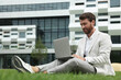 © New Africa - Handsome businessman with laptop on green grass outdoors