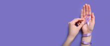Female Hands Holding Awareness Ribbon On Lilac Background With Space For Text. World Cancer Day