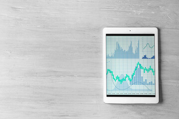 Wall Mural - Modern tablet computer with stock data on grey wooden background. Finance trading