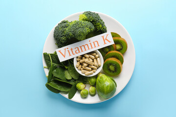 Wall Mural - Plate with healthy products, pills and text VITAMIN K on blue background