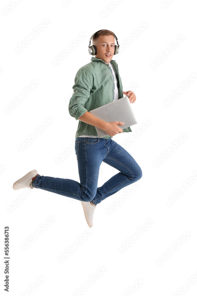 Young man with headphones and laptop jumping on white background. Online education