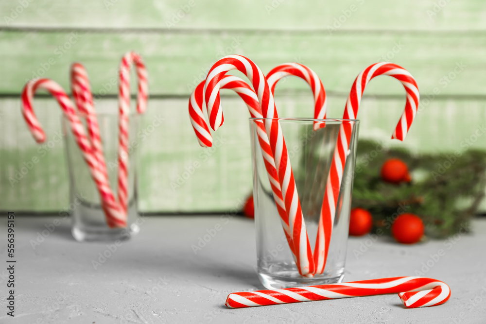 Glass of sweet candy canes on table