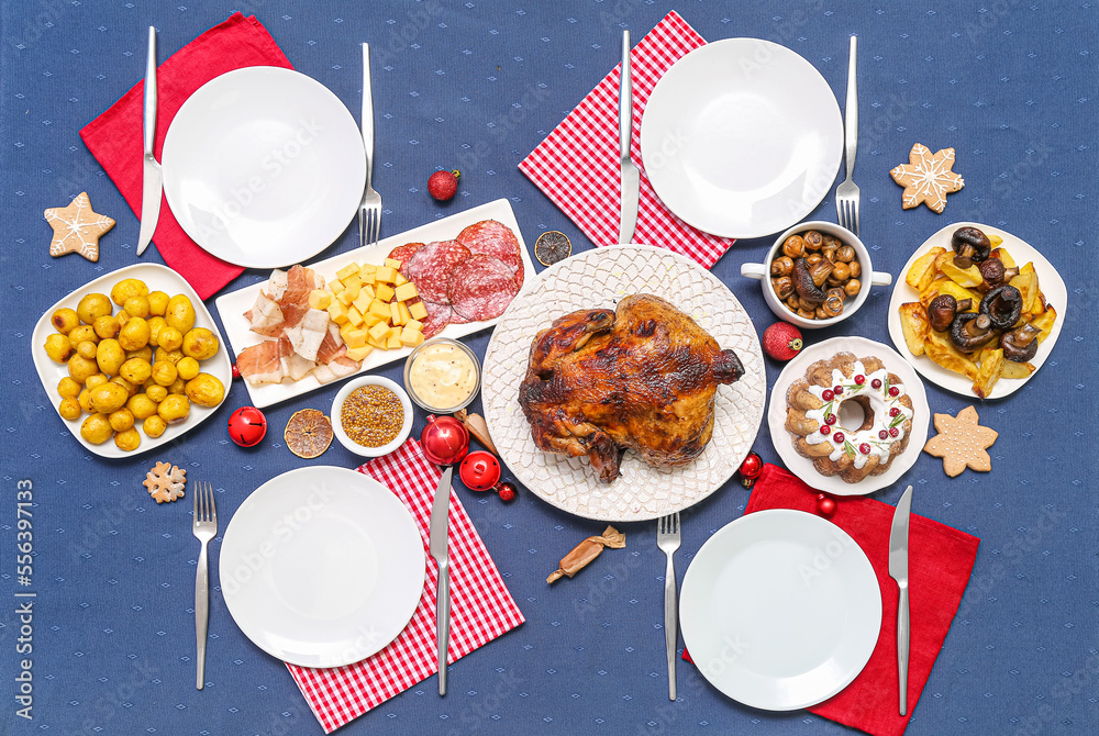 Christmas table setting with tasty food and decor on blue cloth