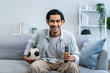 © Kawee - Asian attractive man watching football sport game on television at home.
