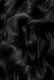 Brunette or black hair. Female long dark hair in black. Beautifully laid curls. Closeup texture in a dark key. Hairdressing, hair care and coloring. Shading gray hair. Background with copy space.