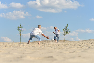 Poster - Portrait of a senior couple with ball on blue sky background