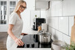 © brizmaker - woman cooking with induction stove at home kitchen