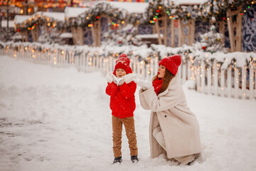 mother and son in warm clothes have fun in winter at a snowy New Year's fair on Red Square in Moscow